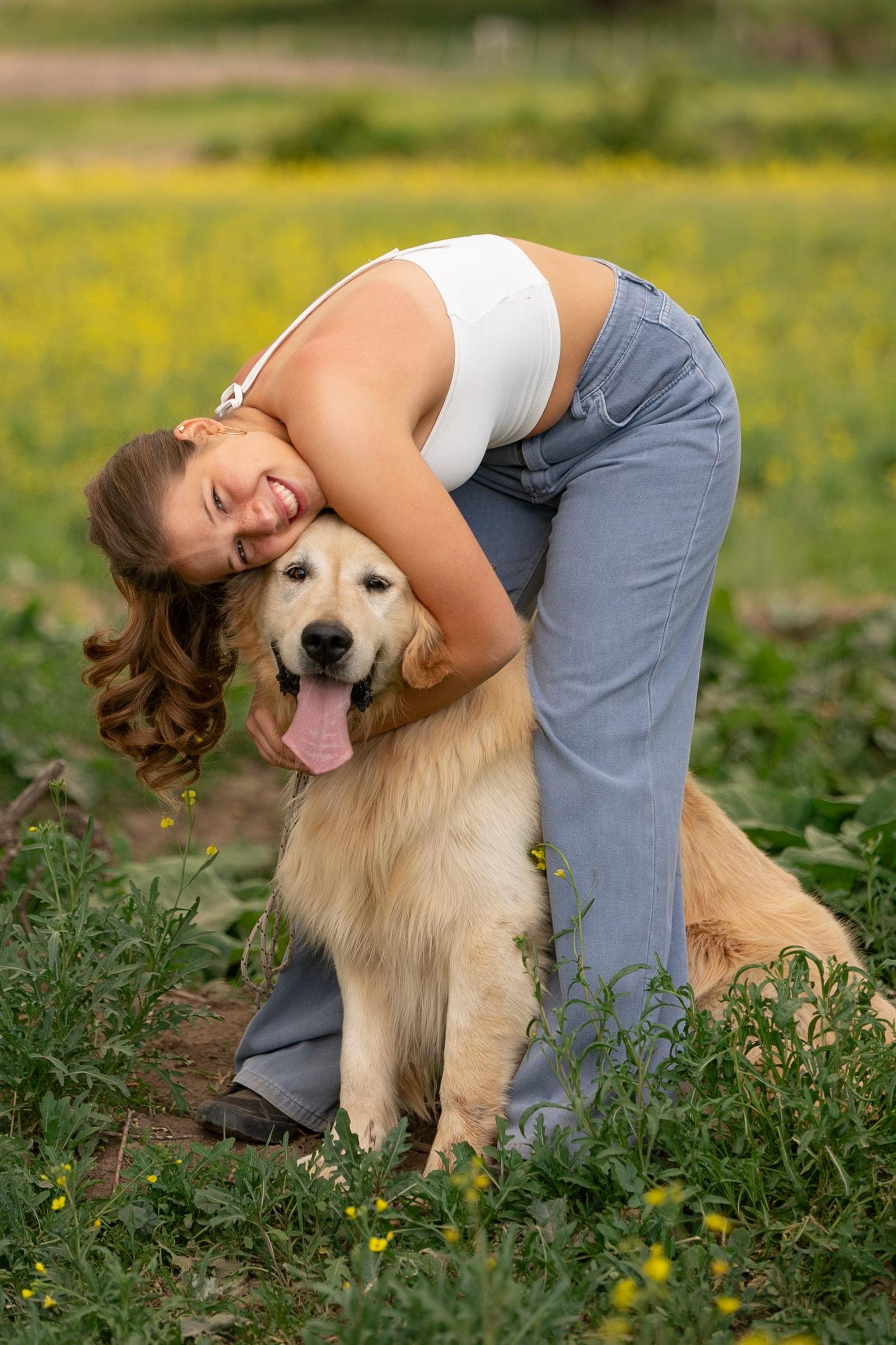 Woman hugging her Golden Retriever in a field of flowers